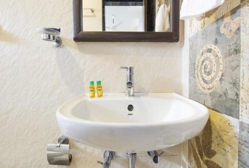 a white sink in a bathroom with a mirror at Aravind Residency Calangute in Goa