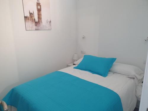 - un lit avec un oreiller bleu et une photo sur le mur dans l'établissement CASA GREGO, à La Vera