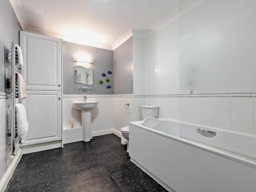 a white bathroom with a tub and a sink at 3 Bed in Newquay SPINS in Newquay