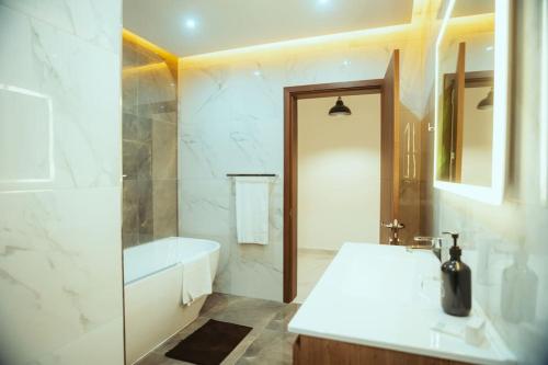 a white bathroom with a tub and a sink and a bath tub at Luxurious Gozo Apartment, Qala in Qala