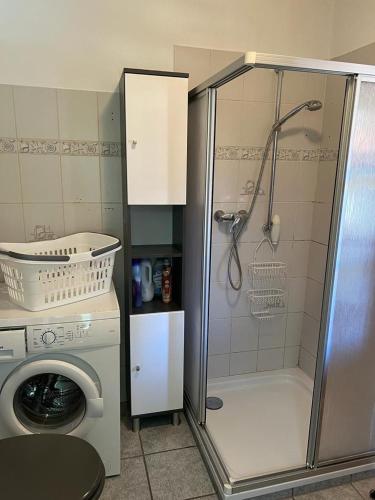 uma casa de banho com um chuveiro e uma máquina de lavar roupa em Schicke Ferienwohnung im Wendland 