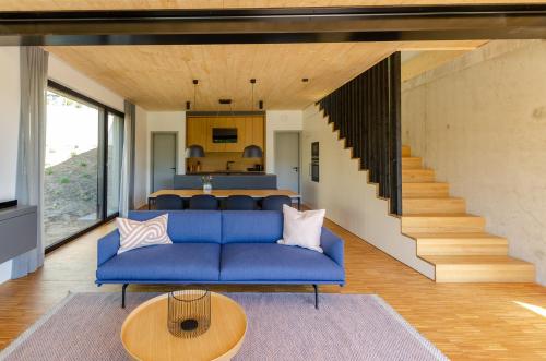 a living room with a blue couch and a staircase at Sauerland Lodge - Haus Anton in Winterberg