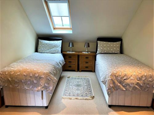 a attic bedroom with two beds and a window at 2 Bed in Looe LANDC in Duloe