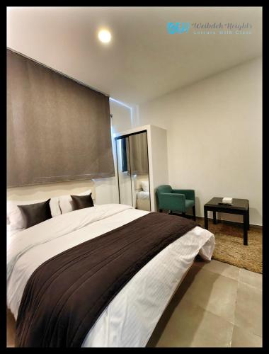 a bedroom with a large bed and a green chair at Weibdeh Heights Apartments in Amman