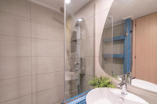 La salle de bains est pourvue d'une douche, d'un lavabo et d'un miroir. dans l'établissement City Oasis: Newly Renovated 2Br Apt in City Center, à Athènes