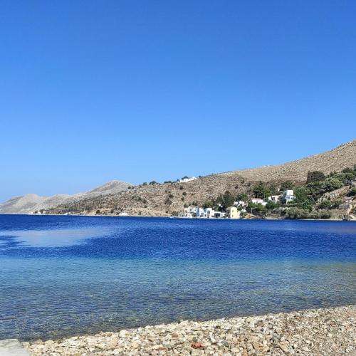 a large blue lake with houses in the background at Petridi House in Symi