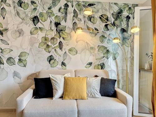 - un canapé dans le salon orné d'un mur fleuri dans l'établissement Le Longchamp, à Deauville