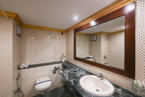La salle de bains est pourvue d'un lavabo, de toilettes et d'un miroir. dans l'établissement Nahar Heritage Hotel, à Bangalore