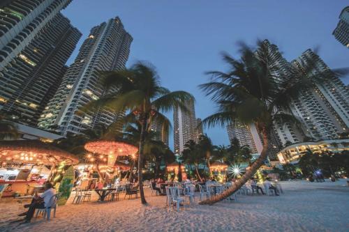 a beach with palm trees and tables and buildings at Dooga Ins-Dreamspace L37 Seaview Projector 1-6pax in Johor Bahru