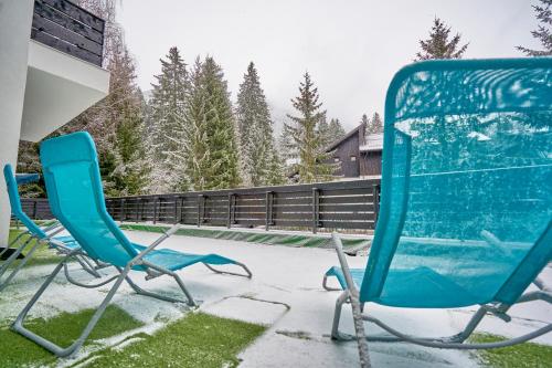 two chairs sitting on a patio in the snow at Family TreeZ Premium Apartments in Poiana Brasov