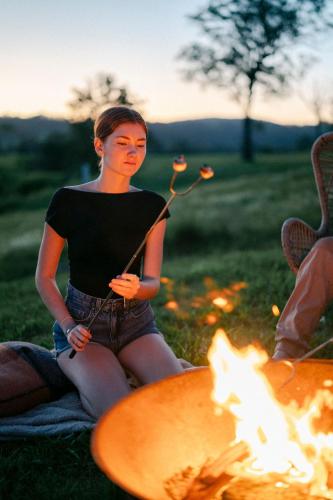 a woman is sitting next to a fire at Whisky @ On The Rocks in Rock Valley