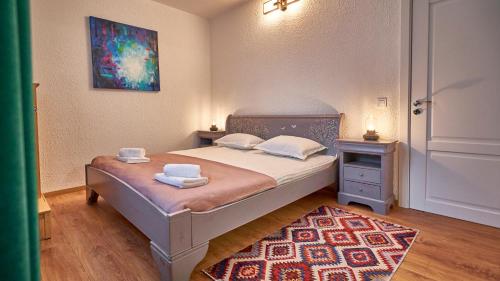 a bedroom with a bed with two towels and a rug at Family TreeZ Premium Apartments in Poiana Brasov