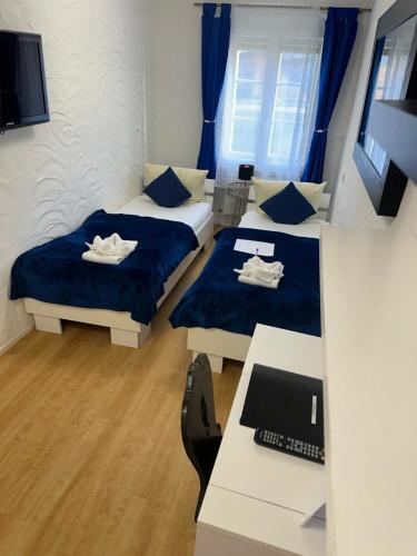 a room with two beds and a desk with a computer at Hotel Zum Goldenen Anker in Bamberg