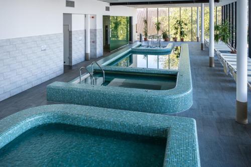 a swimming pool with two jacuzzles in a building at BL Garden Panzió in Balatonlelle
