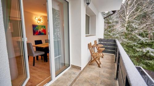 a balcony with a chair and a table and a table at Family TreeZ Premium Apartments in Poiana Brasov
