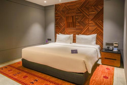 a bedroom with a large white bed with a wooden headboard at Radisson Resort and Spa Lonavala in Lonavala