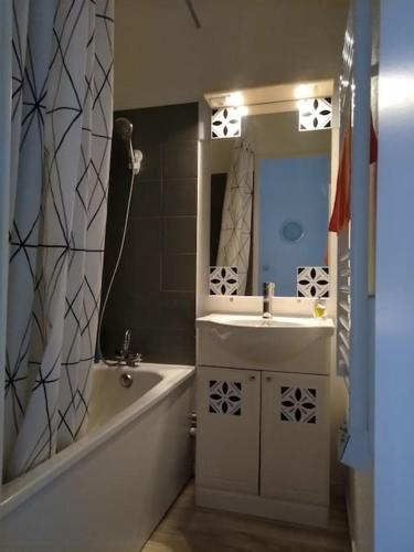 une salle de bain avec une baignoire, un lavabo et un miroir dans l'établissement Maison de vacances en bord de mer, avec piscine, à La Faute-sur-Mer