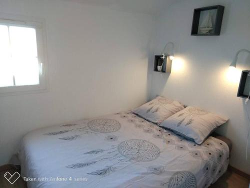 un petit lit dans une chambre avec une fenêtre dans l'établissement Maison de vacances en bord de mer, avec piscine, à La Faute-sur-Mer