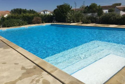 une grande piscine avec de l'eau bleue dans l'établissement Maison de vacances en bord de mer, avec piscine, à La Faute-sur-Mer