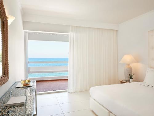 a bedroom with a bed and a view of the ocean at Grecotel LUXME White in Adelianos Kampos