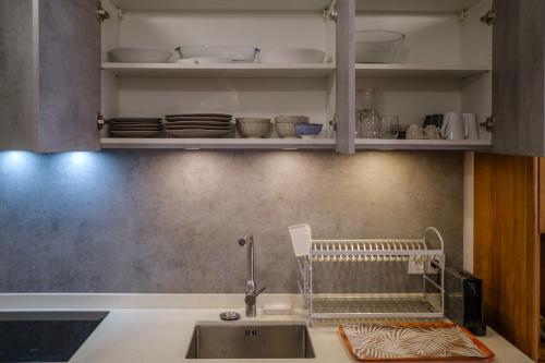 a kitchen with a sink and shelves with dishes at Grand Large - cosy studio in Papeete