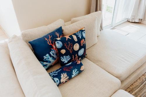 a white couch with three blue pillows on it at Sterretjie in Paternoster