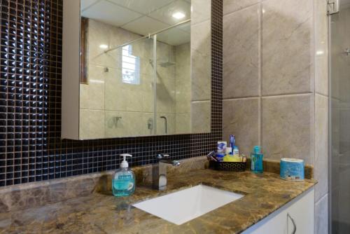 a bathroom with a sink and a shower and a mirror at Swiss Royal Suites in Bangalore