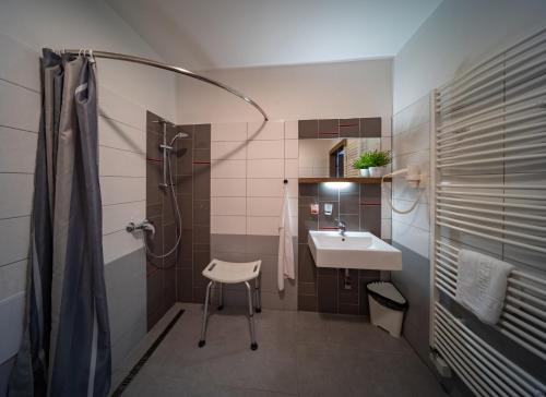 y baño con lavamanos, ducha y silla. en Penzion Zubr en Ujčov
