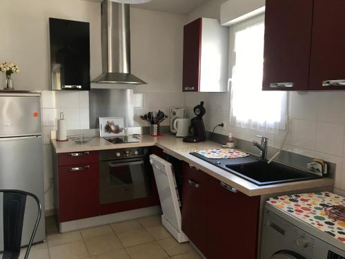 a kitchen with red cabinets and a white refrigerator at 200 M Port de Cassy , studio cosy 3 pers in Lanton