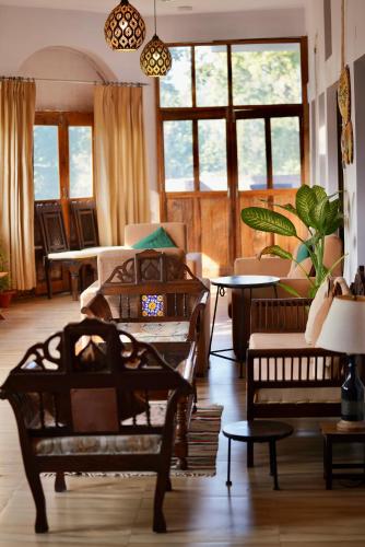 a living room with chairs and tables and windows at The Flying Squirrel Bandhavgarh in Umariā