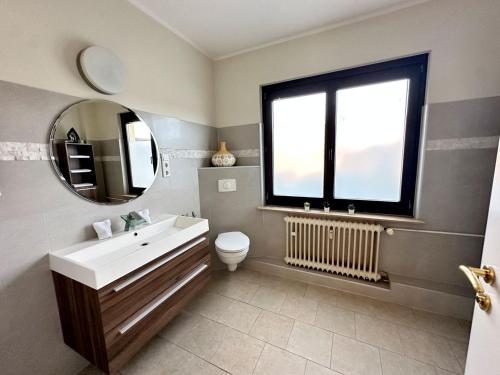 ein Badezimmer mit einem Waschbecken, einem Spiegel und einem WC in der Unterkunft Cozy Apartment Krefeld in Krefeld