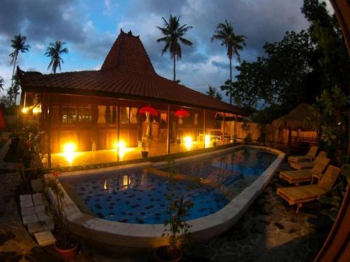 a swimming pool in front of a house at night at Omah Gili Hotel in Gili Air