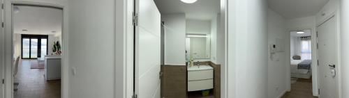 a white bathroom with a sink and a mirror at El Mirador Ría de Vigo, apartamento frente al mar, céntrico in Moaña