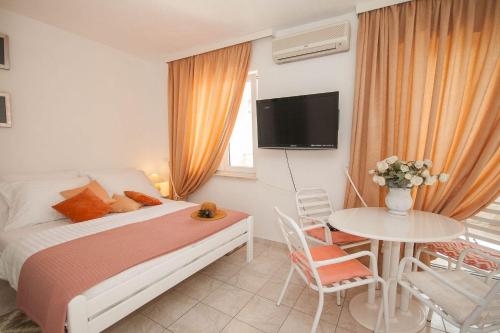 1 dormitorio con cama, mesa y TV en Direkt an der kristallklaren Adria gelegen, en Baška
