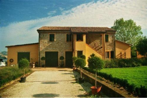 ein großes Haus mit einer Einfahrt davor in der Unterkunft Country House Il Sassòne in Camerano