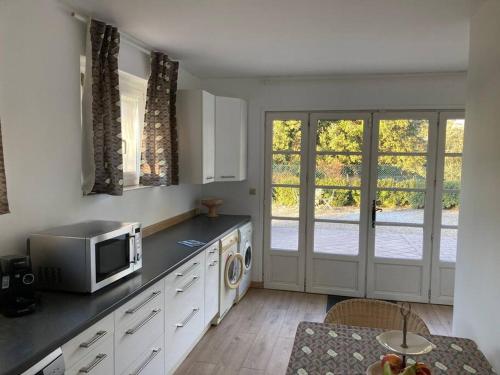 une cuisine avec un four micro-ondes sur un comptoir et une porte dans l'établissement Gîte au milieux des oliviers., à Caromb
