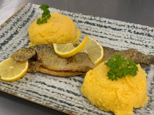 a plate of food with fish and lemon slices at Hotel Dia Lin in Borşa