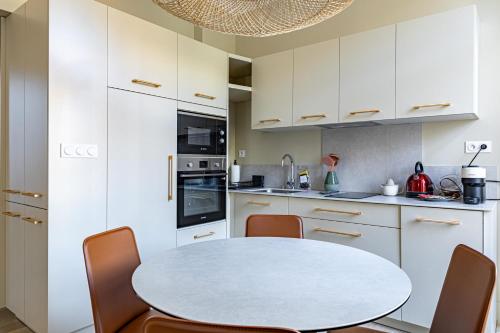 une cuisine avec des armoires blanches et une table et des chaises dans l'établissement LE WINDSOR confortable pour un séjour au calme en centre-ville, à Cannes