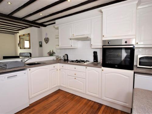 uma cozinha com armários brancos e um micro-ondas preto em 2 Bed in Conwy TYCAN em Llangelynin