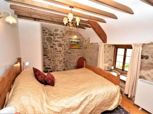 a bedroom with a bed and a stone wall at 3 Bed in Widecombe-in-the-Moor 36683 in Widecombe in the Moor