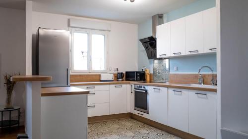 La cuisine est équipée de placards blancs et d'un réfrigérateur en acier inoxydable. dans l'établissement La petite Roche - Spacieux T2 à Poitiers, à Poitiers