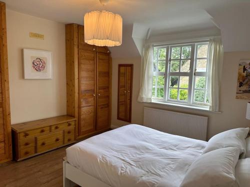 een slaapkamer met een wit bed en een raam bij The Hidden Cottage in Londen