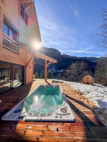 een hot tub op een terras naast een gebouw bij Chalet ECRIN DES VIGNES in Les Vigneaux