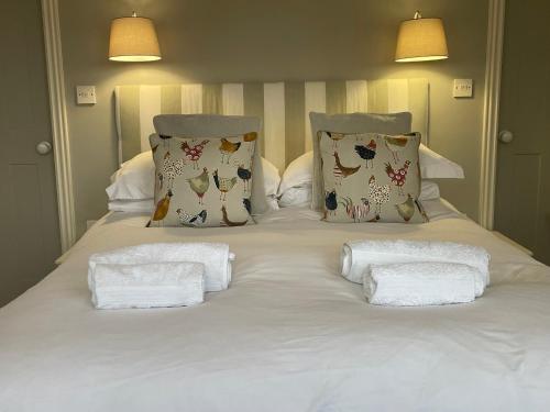 a white bed with pillows and towels on it at Poplars Farm in Henlow