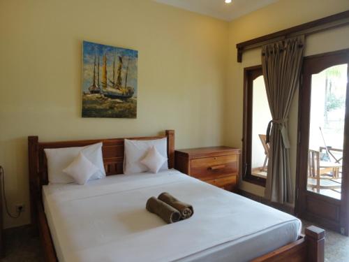 a bedroom with a large white bed with a window at Adinda Bungalows in Gili Air