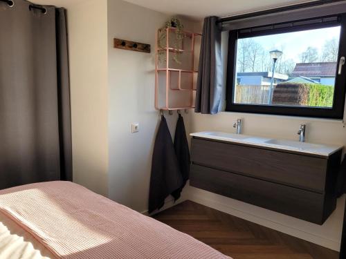 baño con lavabo y ventana en Tiny Zen House in Heinkenszand with private sauna, airco, outdoor swimming pool, WiFi and 2 bedrooms, en Heinkensand