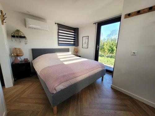 1 dormitorio con cama y ventana grande en Tiny Zen House in Heinkenszand with private sauna, airco, outdoor swimming pool, WiFi and 2 bedrooms en heinkenszand