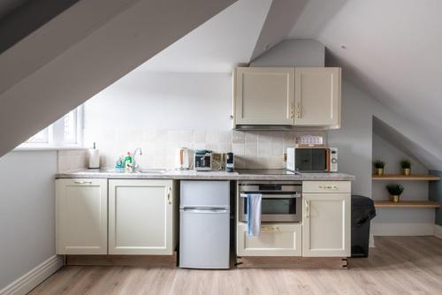 a kitchen with white cabinets and appliances in a attic at CoHost - Sky high in Bristol in Bristol
