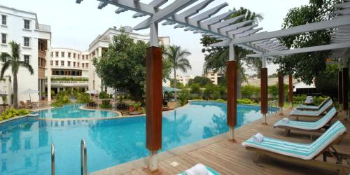una piscina con 2 tumbonas junto a un edificio en The Manohar Hyderabad en Hyderabad