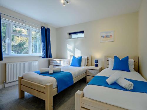 two beds in a bedroom with blue pillows at 2 Bed in Mudeford 93458 in Christchurch